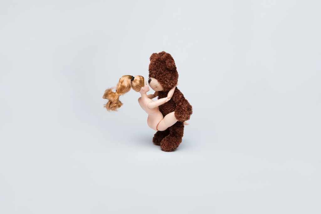 a bear doll holds a naked woman doll a bear doll holding a nude woman doll