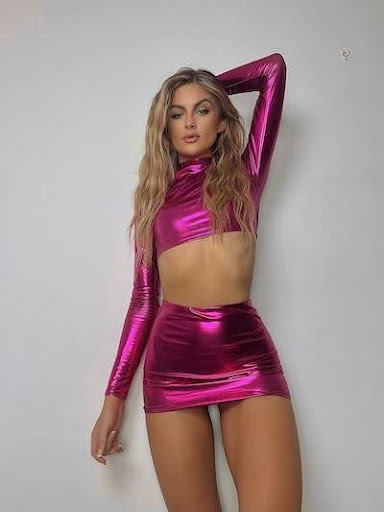 Goddess Leona posing in a shiny pink short skirt and short topic showcasing her plain nude belly and magnificent legs
