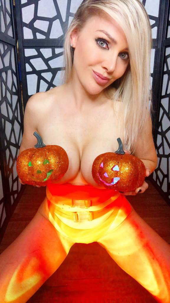 Miss Madison Stone sitting on her knees with naked breasts covered by Halloween pumpkins